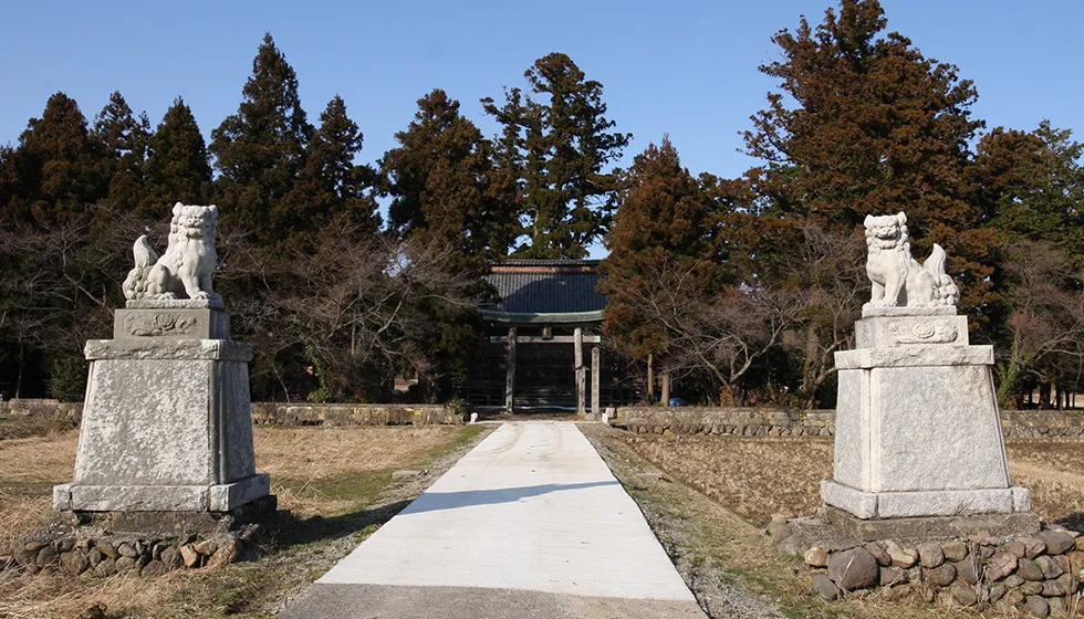 参道を挟んで田んぼに建つ狛犬